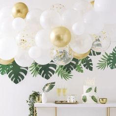 a party table with balloons and greenery