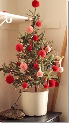 a potted christmas tree with red and pink balls on it's top, sitting on a table