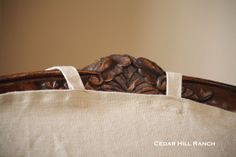 a close up of a wooden headboard on a bed with a white linen pillow