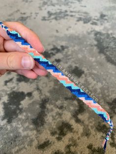 a hand holding a blue, pink and white braided toothbrush