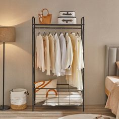 a bedroom with a bed, lamp and clothes rack on the floor in front of it