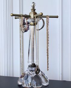 an ornate glass candle holder with beads and chains hanging from it's sides on a black table