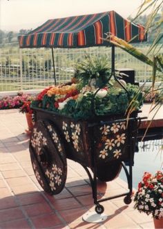 a cart filled with lots of flowers sitting on top of a brick floor next to a pool