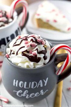 two mugs filled with whipped cream and candy canes on top of a table