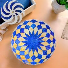 a blue and yellow bowl sitting on top of a table next to a potted plant