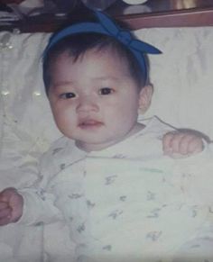 an old photo of a baby with a blue bow on her head