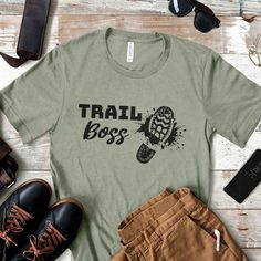 Trail Boss T-Shirt. Looking for a fun gift for a hiking friend or hike leader, a backpacker, or scout leader? Then check out this light and comfy hike lover tee. Bold and funny, it's perfect for wearing while leading hikes, as well as out and about to show who's the "boss" on your hiking adventures. Available in 12 cool colors for every season, this unisex tee looks great on men and women. HOW TO ORDER 1) Choose the shirt size you'd like in the 1st drop down menu. See below for help with Sizing Who's The Boss, Trail Boss, Hiking Adventures, Scout Leader, Mountain Adventure, Boss T Shirt, Cool Colors, Lovers Gift, Campfire