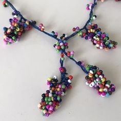 multicolored beaded necklace on white surface with beads hanging from it's sides