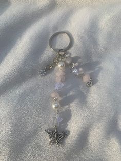 a keychain with a butterfly charm on it's side and beads hanging from the end