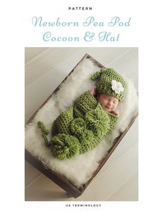 a baby in a green crochet outfit laying on top of a white blanket