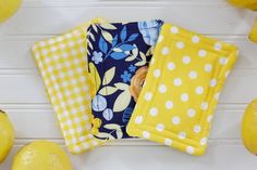 three yellow and blue cloths sitting on top of each other next to lemons