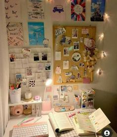 a desk with a keyboard, mouse and various pictures on the wall next to it