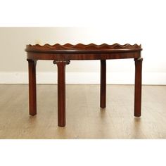 a wooden table with an oval shaped top and two legs on the bottom, sitting on a hard wood floor in front of a white wall