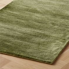 a green rug on top of a wooden floor next to a hardwood flooring area