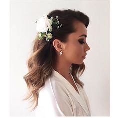 a woman with long hair wearing a white jacket and flower in her hair is looking off to the side