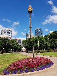 there is a very tall tower in the middle of this park with flowers around it