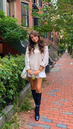 a woman is walking down the sidewalk with her boots on