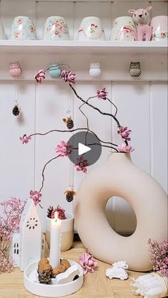 a table topped with white vases filled with flowers and other decorating items on top of a wooden floor