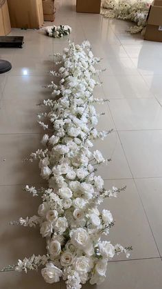 white flowers are lined up on the floor in a long line with boxes behind them