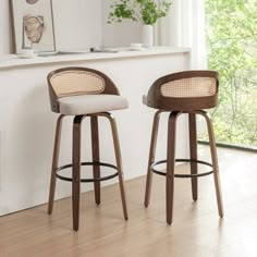 two stools in front of a window with plants on the wall behind them,