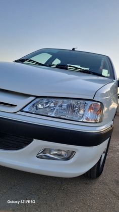 the front end of a white car parked in a parking lot