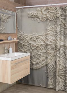 a bathroom with a sink, mirror and shower curtain that has intricate lace on it