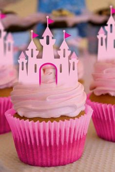 cupcakes with pink frosting and castle decorations on top are sitting on a table