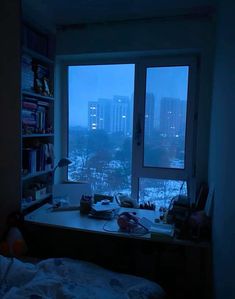 a bedroom with a window that looks out onto the city at night, and there is no one in it