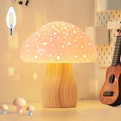 a lamp that is on top of a table next to a ukulele and mushrooms