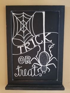 a chalkboard with the words trick or treat written on it and a spider web