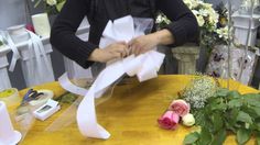 a woman is cutting paper with scissors on a table in front of flowers and other decorations