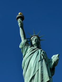 the statue of liberty is shown against a clear blue sky with a gold ball in its hand