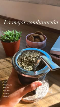 a person is holding a bowl with food in it and some plants on the table