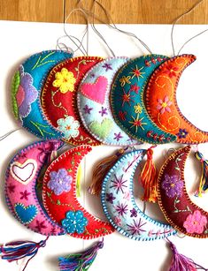 a bunch of colorful ornaments are hanging on a table with some string attached to them