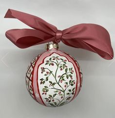 a red and white ornament with a bow on it's side is shown