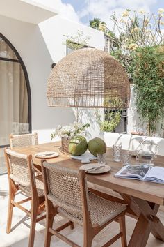 an outdoor dining area with wicker chairs and wooden table