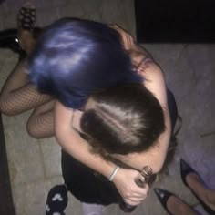 a woman with blue hair and fishnet stockings is hugging her head on the floor