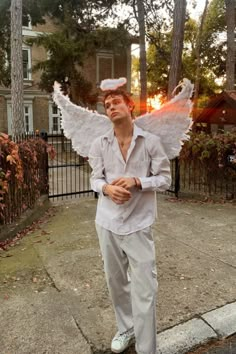 a man dressed as an angel standing on the sidewalk