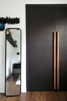 a large mirror sitting on top of a wooden floor next to a black door in a room