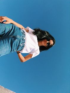 a woman in white shirt and jeans standing on top of a ramp with skateboard