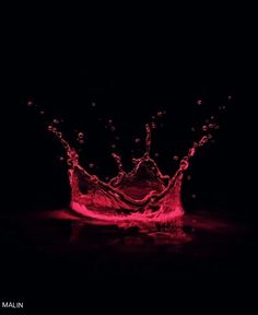 a red water splashing on top of a black surface