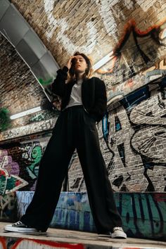 a woman standing in front of graffiti covered walls