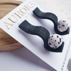 two black and white polka dot hair clips sitting on top of a wooden tray next to a magazine