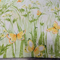 a green and yellow butterfly print fabric on a wooden tablecloth with white flowers in the background