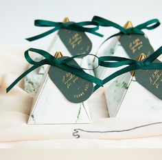 three tags tied to each other on top of a white table cloth with green ribbons