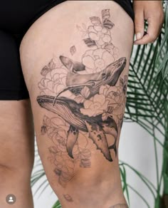 a woman's thigh with a whale and flowers tattoo on it