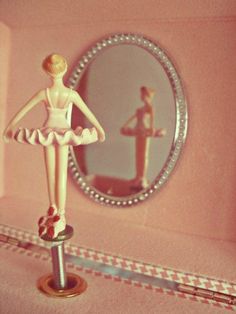 a ballerina doll standing in front of a mirror