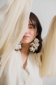 a woman wearing large white flowers on her earrings