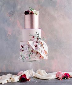 a three tiered wedding cake with flowers on top and napkins around the edges