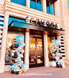 the entrance to a store decorated with balloons and streamers in blue, white and black colors